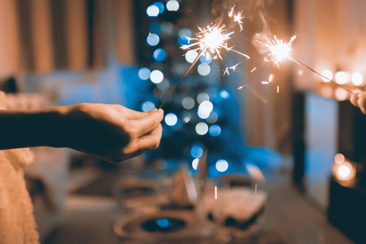 Employees holding sparklers at a remote office holiday party